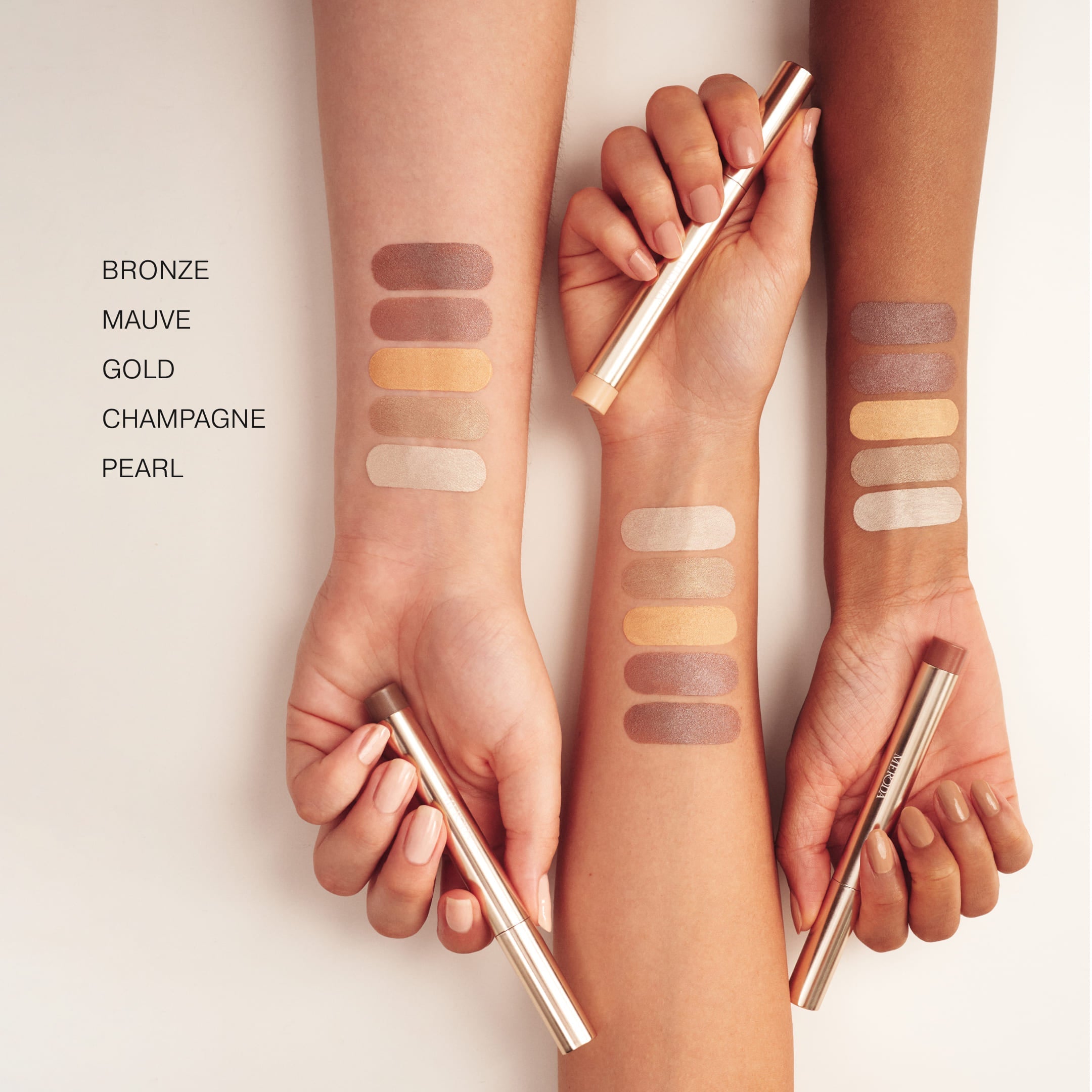 The Power Trio: Eye Perfecting Shimmer Stick swatches in Bronze, Mauve, Gold, Champagne en Pearl op drie huidtinten.