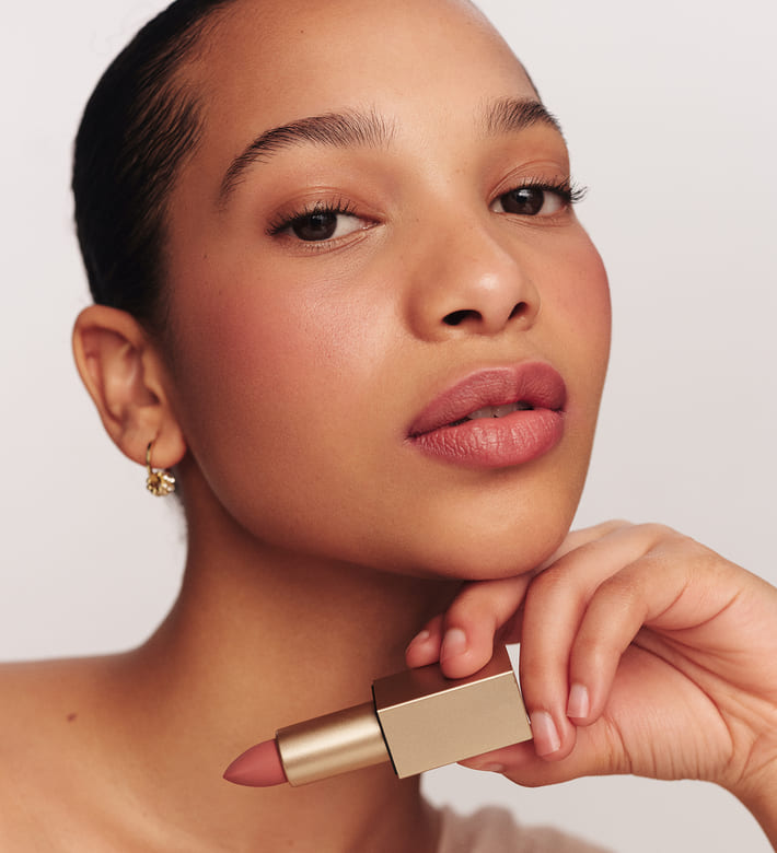 Velvet Dream Lipstick in Perfect Nude vastgehouden door een model met een zachte matte finish en natuurlijke mauve kleur.